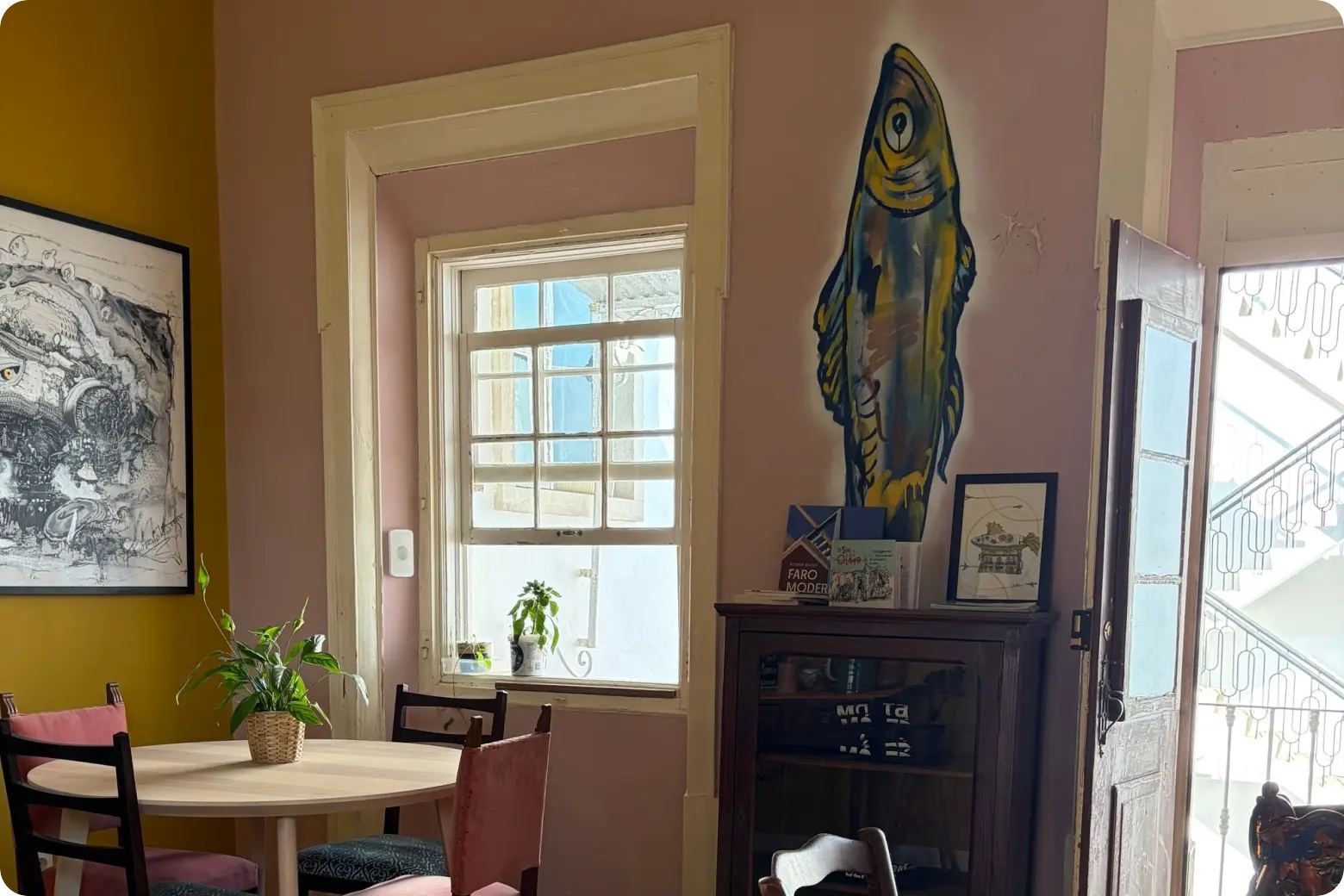 Café room with round tables and a painted fish at A Fábrica coworking in Olhão