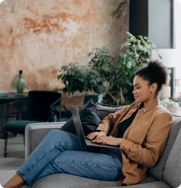 소파에 앉아 노트북을 사용하는 여성