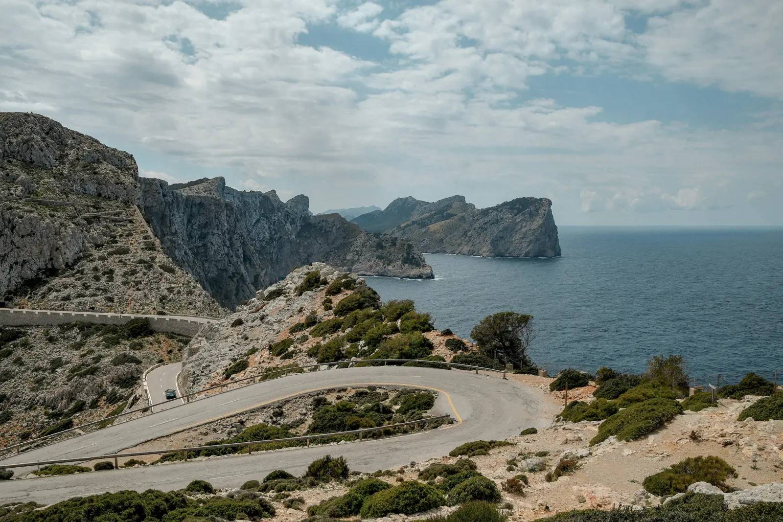 Car on a hairpin coastal road above the sea at Cap de Formentor, Mallorca, Spain