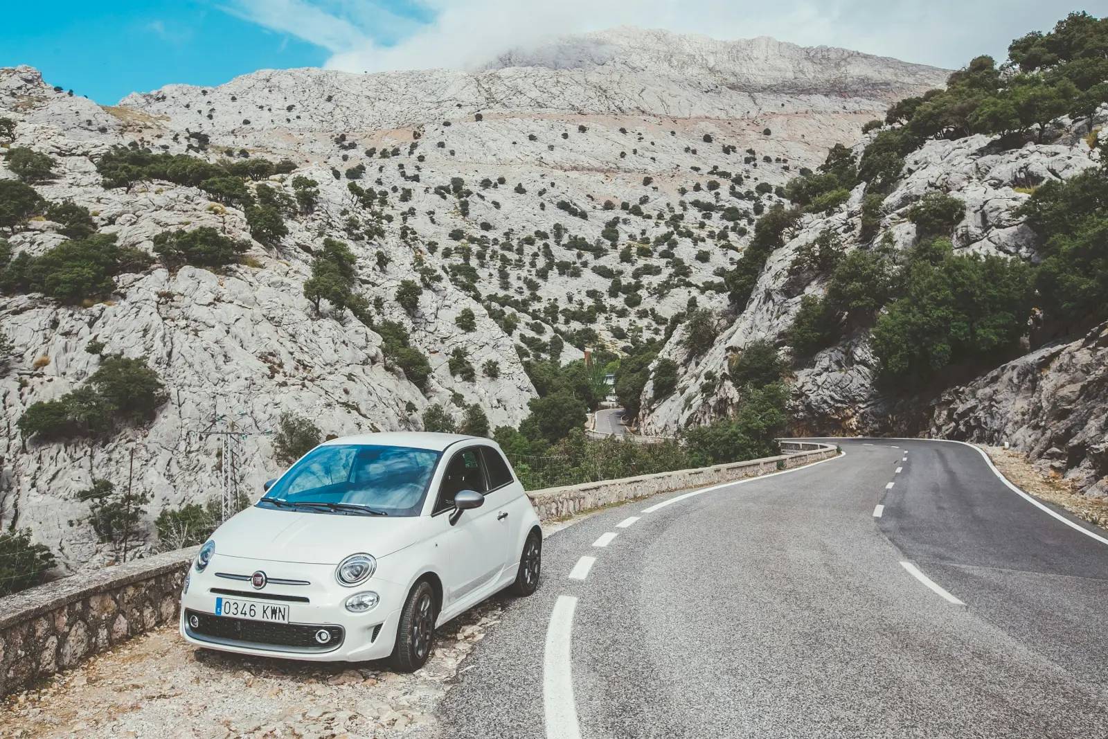 Piccola auto bianca parcheggiata accanto a una strada di montagna tortuosa a Maiorca, in Spagna