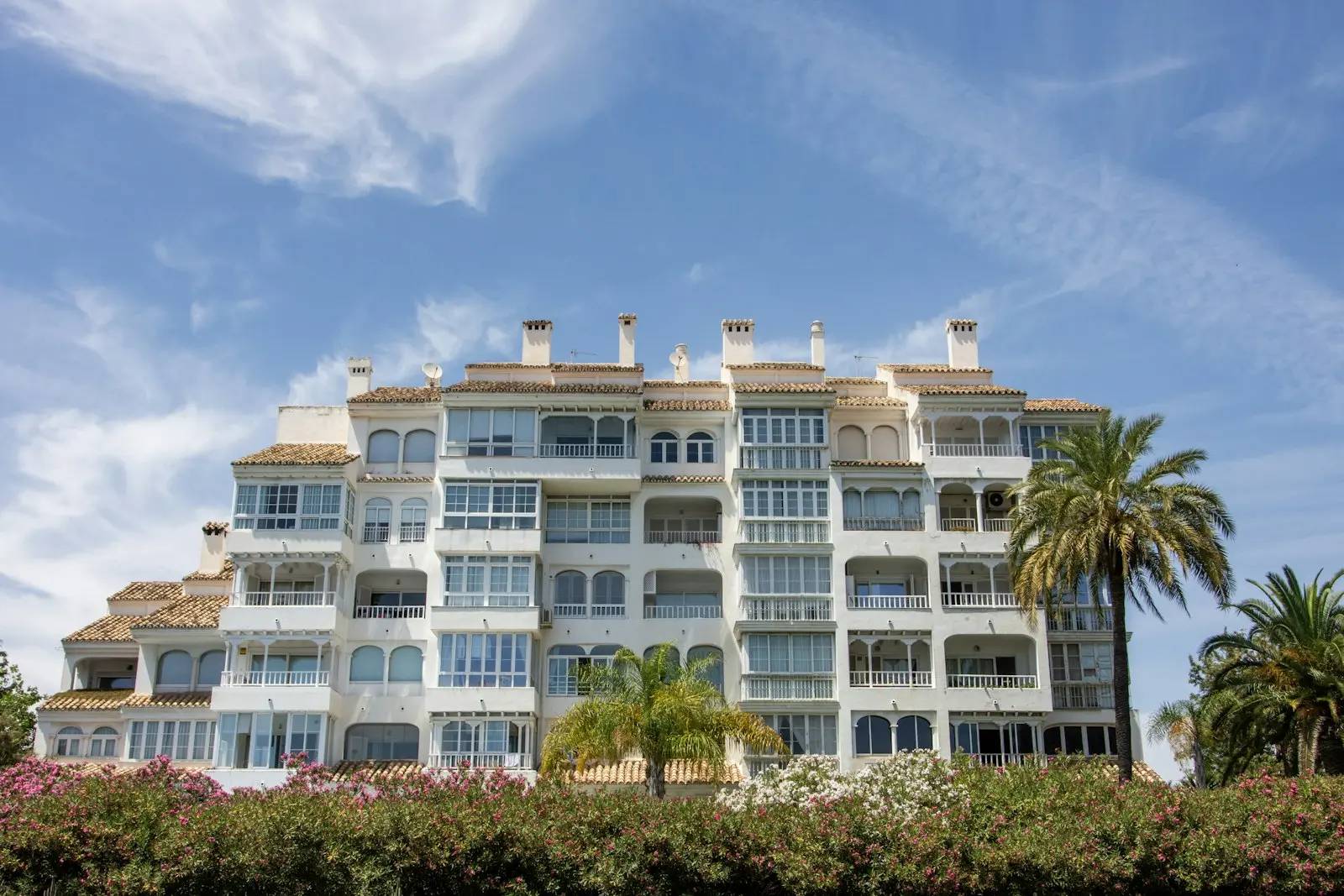 Vit flerfamiljshus med balkonger och palmer i Marbella, Spanien